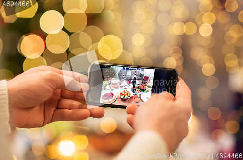 Image of hands photographing food at christmas dinner