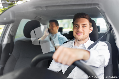 Image of male driver driving car with passenger