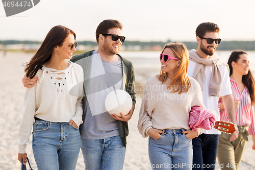 Image of happy friends walking along summer beach