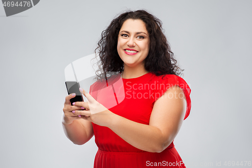 Image of happy woman in red dress using smartphone