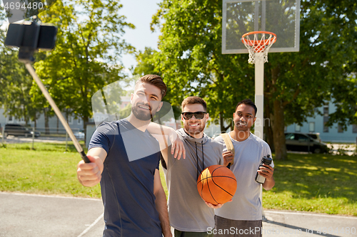 Image of happy men taking selfie on basketball playground