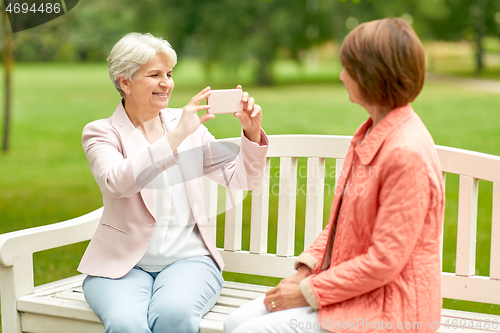 Image of senior woman photographing her friend at park