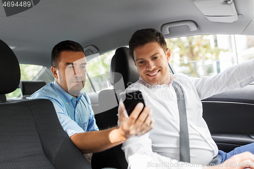 Image of male passenger showing smartphone to car driver