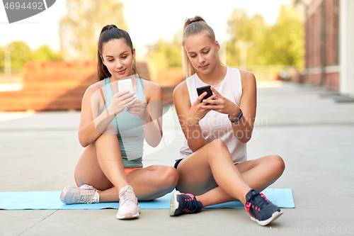 Image of sporty women or friends with smartphone on rooftop