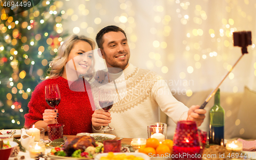 Image of couple taking picture by selfie stick at christmas