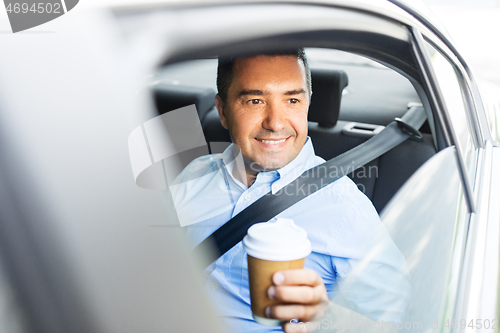 Image of businessman with takeaway coffee on car back seat