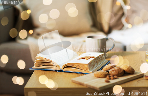 Image of book with autumn leaf, cookies and tea on table