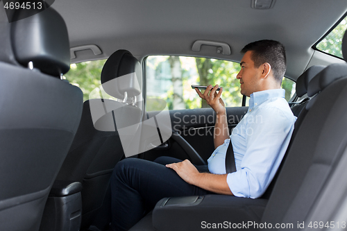 Image of male passenger calling on smartphone in taxi car