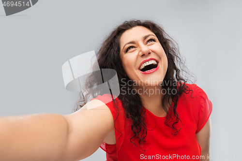 Image of happy woman in red dress taking selfie