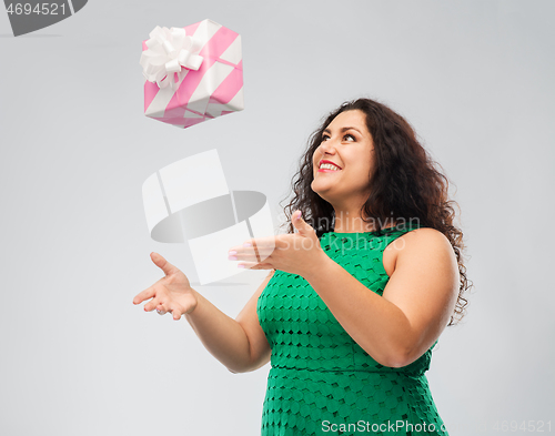 Image of happy woman in green dress playing with gift box