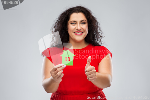 Image of woman holding green house and showing thumbs up