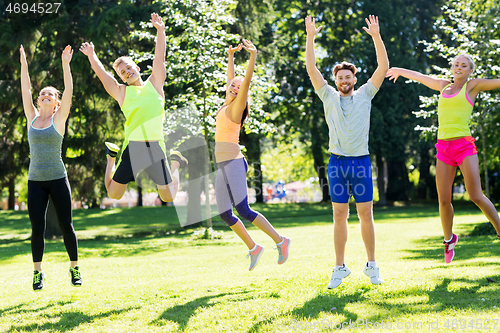 Image of group of happy friends jumping high at park