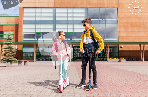 Image of school children with backpacks riding scooters