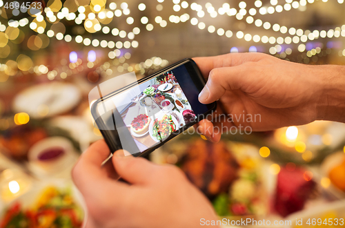 Image of hands photographing food at christmas dinner