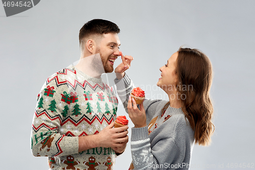 Image of couple with cupcakes in ugly christmas sweaters