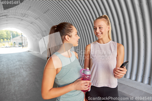 Image of women or female friends with smartphone and flask