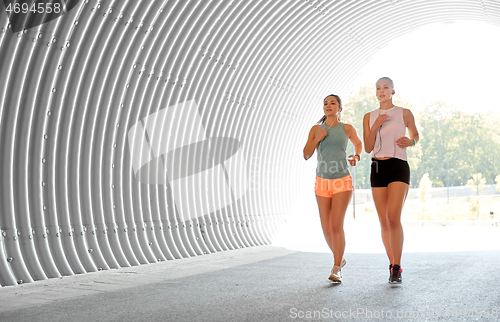 Image of women or female friends with earphones running