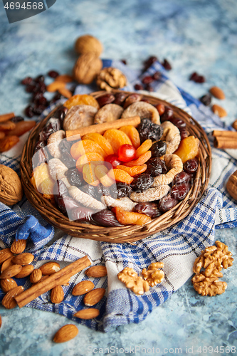 Image of Composition of dried fruits and nuts in small wicker bowl placed on stone table