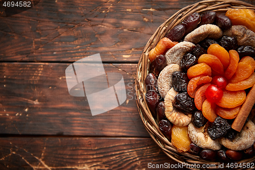 Image of Mix of dried fruits in a small wicker basket on wooden table