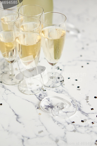 Image of Champagne glasses and bottle placed on white marble background