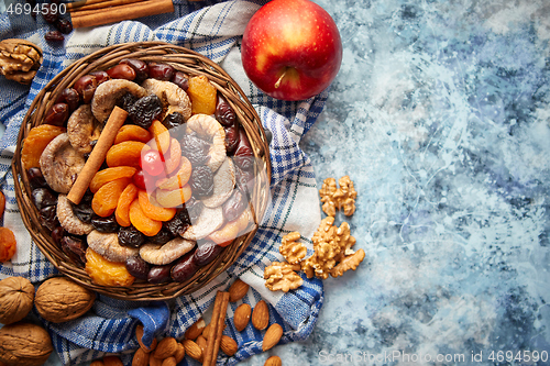 Image of Composition of dried fruits and nuts in small wicker bowl placed on stone table