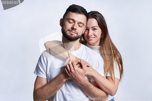 Image of Smiling young couple hugging, studio portrait over light background