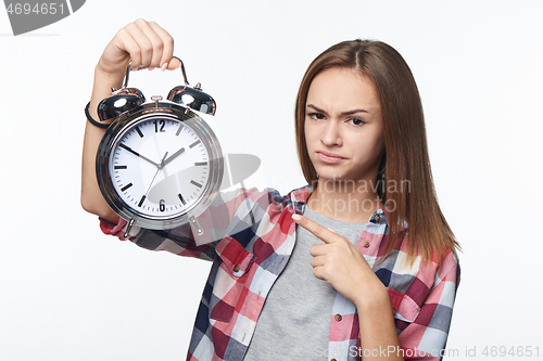 Image of Unhappy teen girl holding big alarm clock pulling discontent face