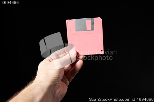 Image of Human hand holding pink floppy disk