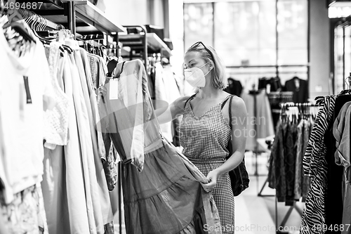 Image of Fashionable woman wearing protective face mask shopping clothes in reopen retail shopping store. New normal lifestyle during corona virus pandemic