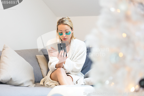 Image of Woman at home relaxing on sofa couch using social media on phone for video chatting with her loved ones during corona virus pandemic. Stay at home, social distancing lifestyle.