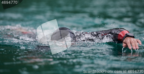 Image of triathlon athlete swimming on lake wearing wetsuit