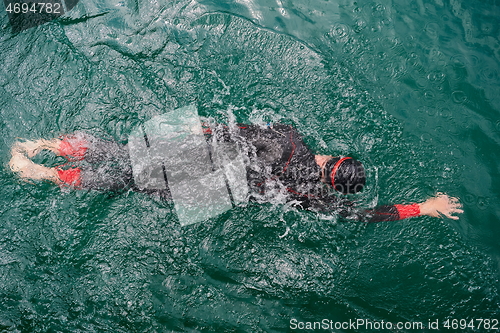 Image of triathlon athlete swimming on lake wearing wetsuit