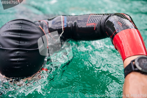 Image of triathlon athlete swimming on lake wearing wetsuit