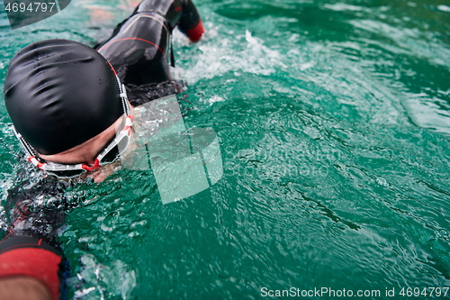 Image of triathlon athlete swimming on lake wearing wetsuit