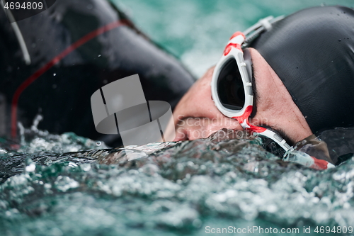 Image of triathlon athlete swimming on lake wearing wetsuit