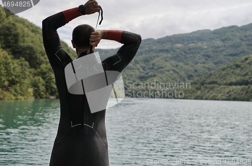 Image of triathlon athlete getting ready for swimming training on lake