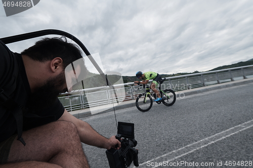 Image of videographer taking action shot of triathlon bike athlete