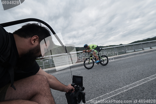 Image of videographer taking action shot of triathlon bike athlete