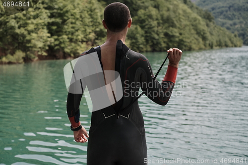 Image of triathlon athlete getting ready for swimming training on lake