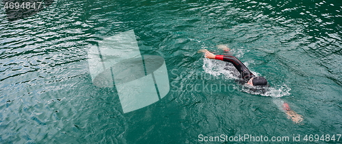 Image of triathlon athlete swimming on lake wearing wetsuit