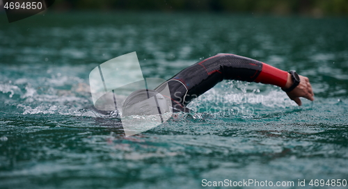 Image of triathlon athlete swimming on lake wearing wetsuit