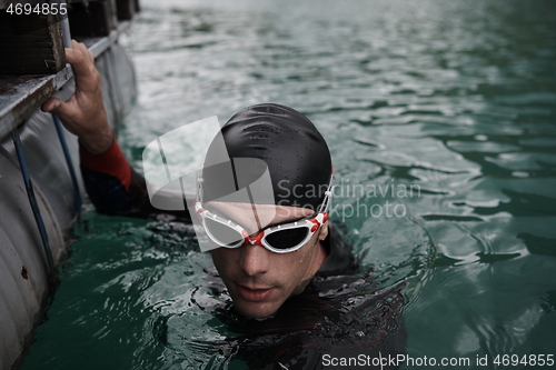 Image of triathlon athlete swimming on lake wearing wetsuit