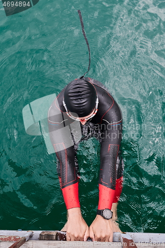 Image of triathlon athlete swimming on lake wearing wetsuit