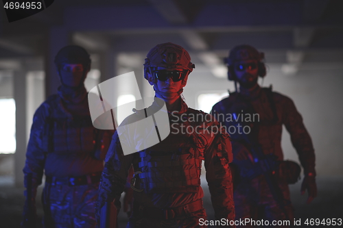 Image of soldier squad team walking in urban environment colored lightis