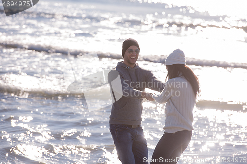 Image of Loving young couple on a beach at autumn sunny day