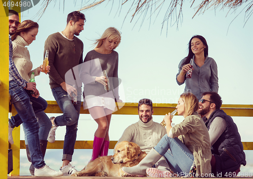 Image of Group of friends having fun on autumn day at beach