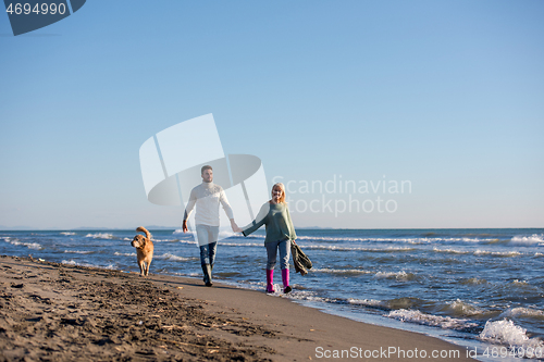 Image of couple with dog having fun on beach on autmun day