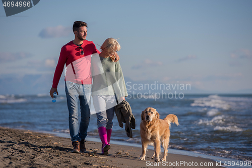 Image of couple with dog having fun on beach on autmun day