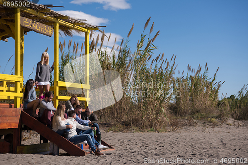 Image of Group of friends having fun on autumn day at beach