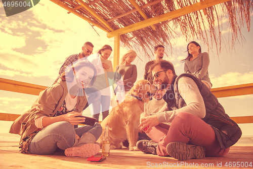 Image of Group of friends having fun on autumn day at beach